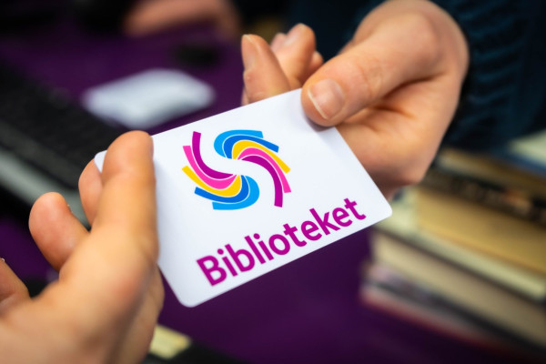 Hånd som gir eit lånekort til ei anna hand: lånar som får nytt kort