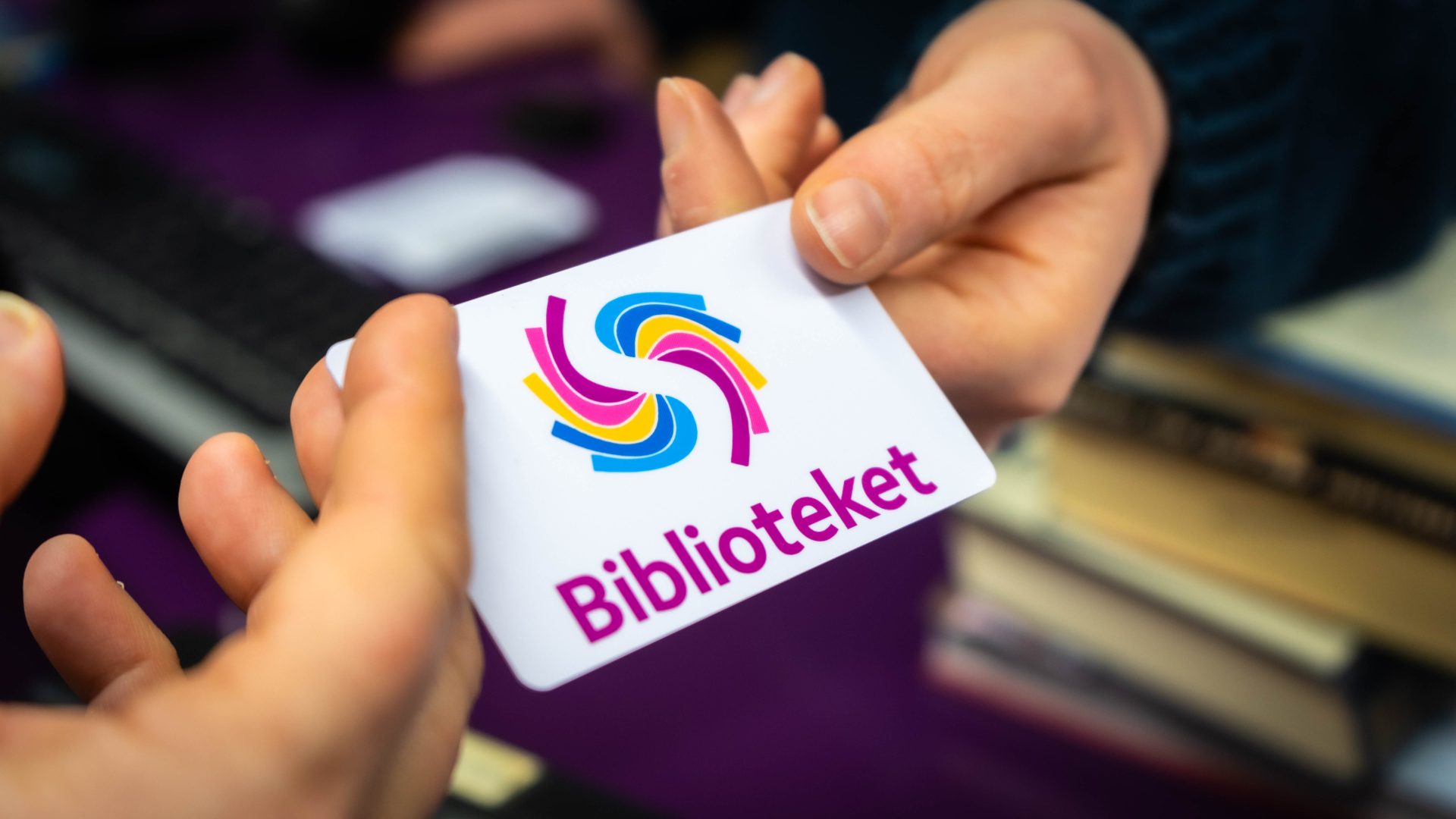 Hånd som gir eit lånekort til ei anna hand: lånar som får nytt kort