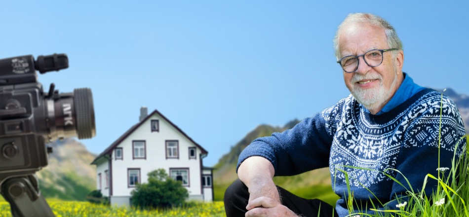 Oddgeir Bruaset sit føre barndomsheimen med eit kamera som peikar på seg.
